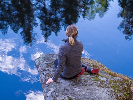 Woman sitting on a rocky ledge above the clouds