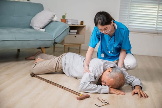 Disabled elderly man patient with walking stick fall on ground and caring assistant at nursing house, Asian senior old man falling down on lying floor and woman nurse helping support in living room