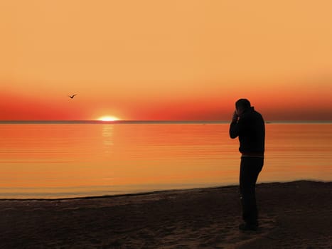 Back view of a silhouette of a man photographing the sun at sunset on the beach on holidays.