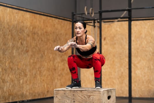 Horizontal photo with copy space of a tattooed woman exercising using box in a cross training gym