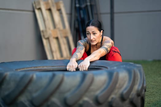 Strong mature woman about to flip a tire in a cross training gym