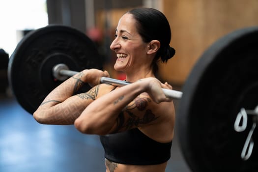 Close-up photo of a smiling mature woman lifting weights in a cross training gym
