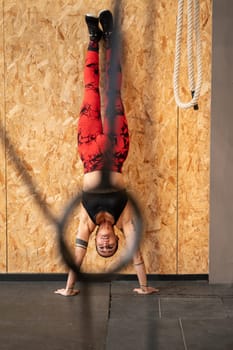 Woman training equilibrium and strength in a gym performing handstand exercise in the wall