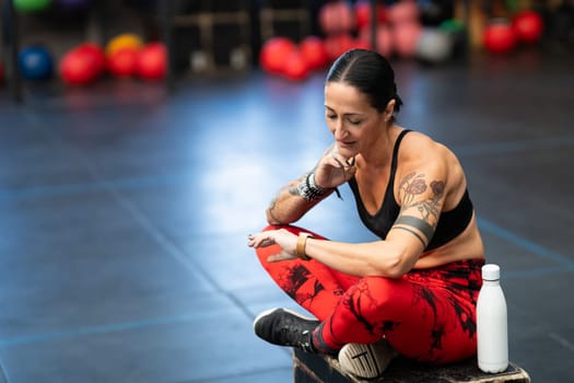 Sportive woman tracking her pulse using a watch after training in the gym