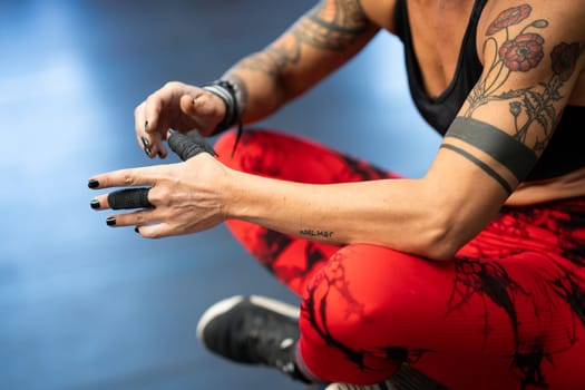 Close-up of athlete protecting her fingers with tape while sitting in the gym