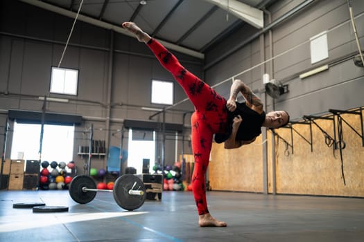 Horizontal photo with copy space of a sportive woman kicking in the air in a gym