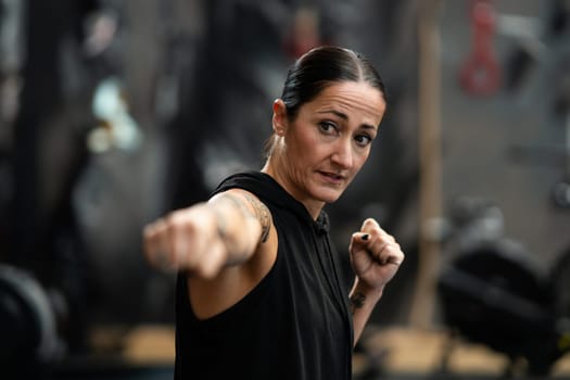 Portrait with focus on a concentrated female boxer throwing a jab while shadowboxing in the gym