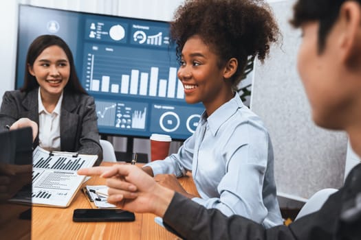 Multiracial analyst team use BI dashboard data to analyze financial report on meeting table. Group of diverse business people utilize data analysis by FIntech for business marketing decision. Concord