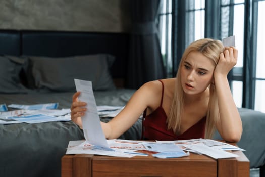Stress worried young woman sit at table, as she pay bills online with credit card from financial debt problem, monthly expense and credit card debt. Over spending money lifestyle problem. Blithe