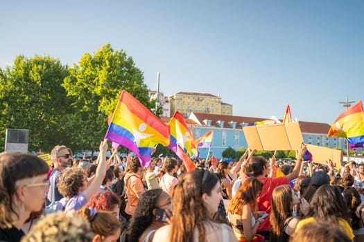 Lisbon, Portugal. 17 June 2023: People holding posters and waving rainbow flags at Pride Parade. Crowds at event to fight for LGBTQAI rights. Support, respect, pride LGBTQAI persons