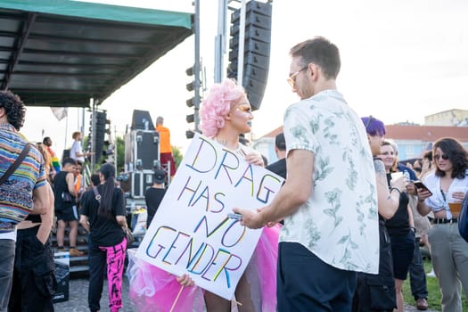 Lisbon, Portugal. 17 June 2023 Drag queen holding poster DRAG HAS NO GENDER at Pride Parade. European drag queen talking with friend standing in crowd at Pride Parade. Respect, sexual equality