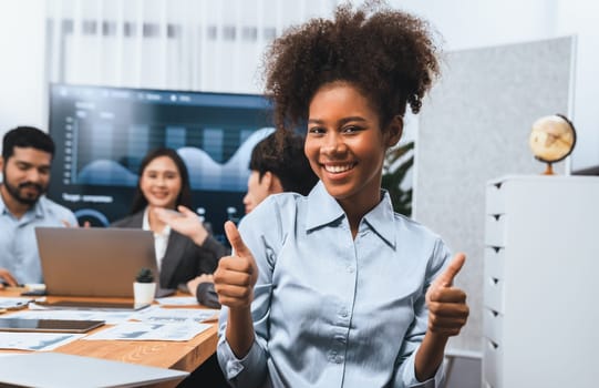 Portrait of happy young african businesswoman with group of office worker on meeting with screen display business dashboard in background. Confident office lady at team meeting. Concord