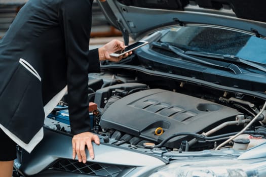 Young businesswoman whose car breakdown uses mobile phone to call for roadside assistance service. Travel and transportation vehicle problem. uds