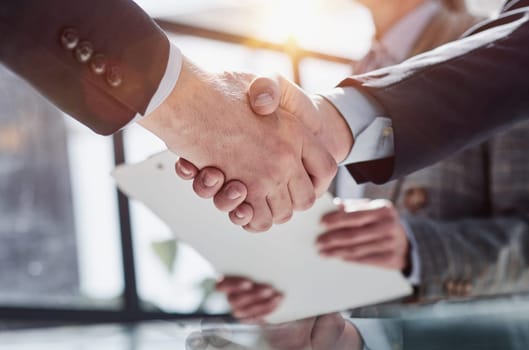 executives shaking hands in front of their manager and a colleague