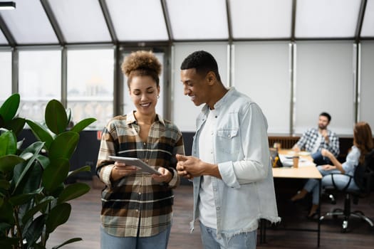 Group of diverse businesspeople using a laptop while working together in a modern workspace.