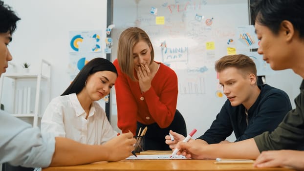 Creative happy business team brainstorming and sharing idea by using mind map and graphic graph while young beautiful project manager pointing at important point at business meeting. Immaculate.