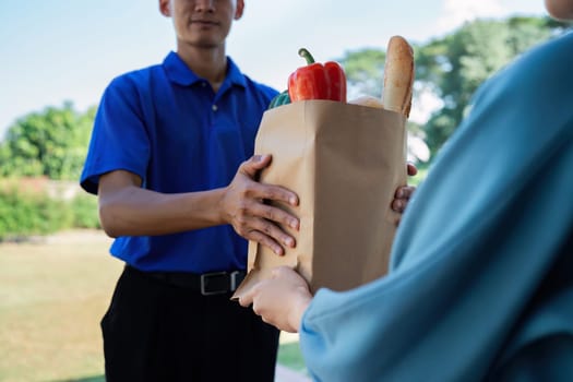 Asian young delivery man delivering package to female customer at home.