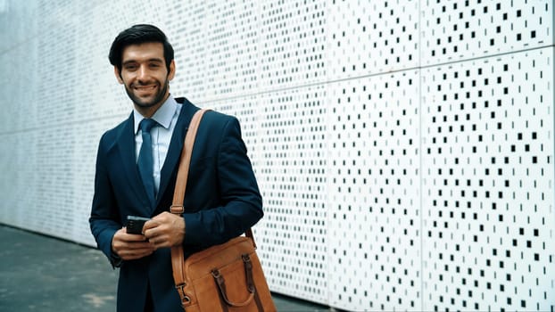 Portrait image of successful young business man looking at camera while hold phone with white background. Attractive caucasian investor or project manager standing at building. Close up. Exultant.