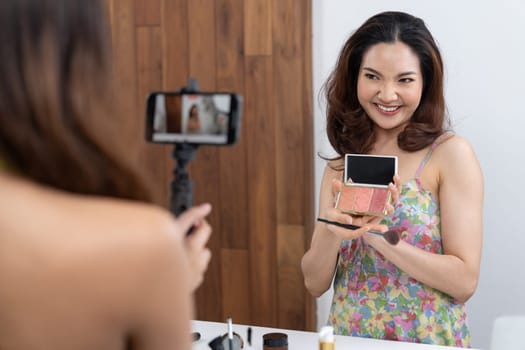 Asian Woman influencer shoot live streaming vlog video review makeup uttermost social media or blog. Happy young girl with cosmetics studio lighting for marketing recording session broadcasting online