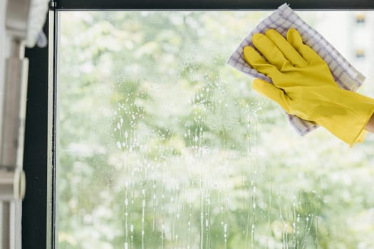 A cheerful maid sprays and wipes office windows ensuring purity and transparent cleanliness. Her dedication to housework emphasizes hygiene and sparkling windows.