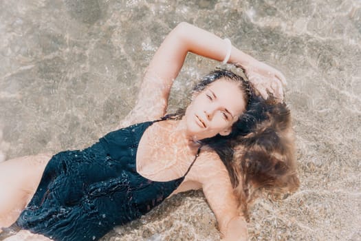 Woman travel sea. Young Happy woman in a long red dress posing on a beach near the sea on background of volcanic rocks, like in Iceland, sharing travel adventure journey