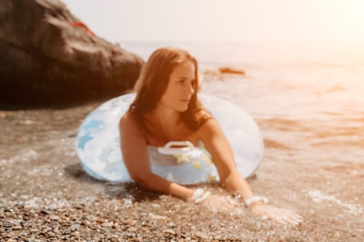 Woman summer sea. Happy woman swimming with inflatable donut on the beach in summer sunny day, surrounded by volcanic mountains. Summer vacation concept