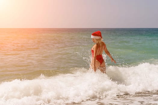 A woman in Santa hat on the seashore, dressed in a red swimsuit. New Year's celebration in a hot country.
