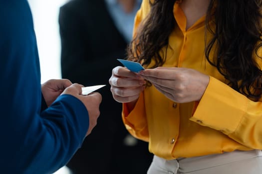 Successful businesswoman holding the name card during talking to manager about their cooperation. Cropped image of exchanging name card between businessman and businesswoman. Side view. Intellectual.