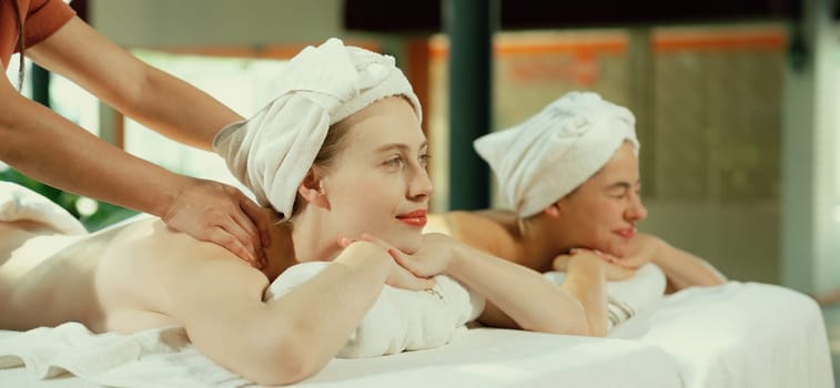 Couple of beautiful young woman lie on white spa bed during having back massage. Attractive caucasian woman having back massage at traditional spa room. Relaxing and healthy concept Tranquility.