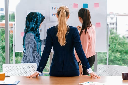 Multicultural working group. Team of businesswomen of different ethnicity, Caucasian, Asian and Arabic working together in team meeting at office. Multiethnic teamwork concept. uds