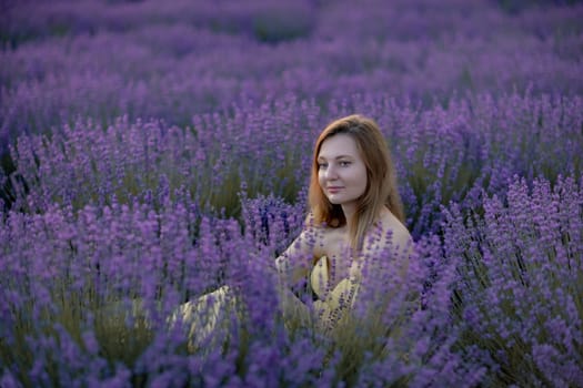 Woman poses in lavender field. Happy woman in yellow dress holds lavender bouquet. Aromatherapy concept, lavender oil, photo session in lavender.