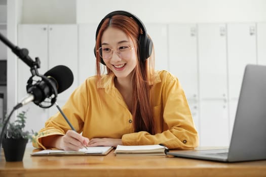 Cheerful woman hosting a live podcast, engaging with audience using professional microphone in studio.