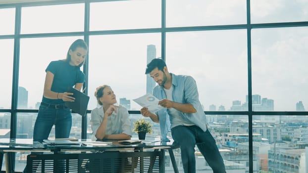 Group of happy skilled businesspeople discuss, brainstorming, sharing idea, plan, strategy about financial statistic on meeting table with laptop and statistic document. Cityscape view. Tracery