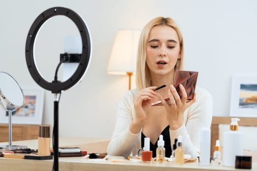 Young woman making beauty and cosmetic tutorial video content for social media. Beauty blogger smiles to camera while showing how to beauty care to audience or followers. Blithe