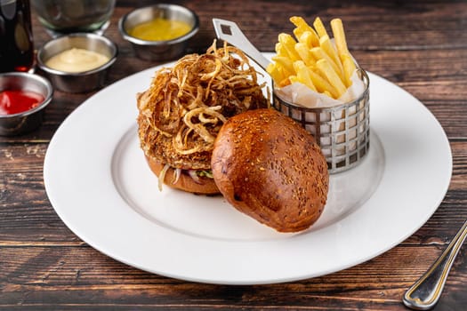 Vegan burger with crispy onions, side sauces and fries