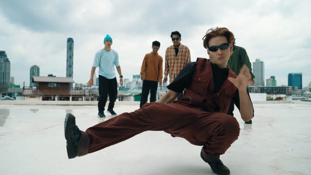 Professional asian street dancer practice B boy dance while multicultural friends at roof top. Young modern dancing group doing hip hop movement. Style,fashion,action. Outdoor sport 2024. Endeavor.
