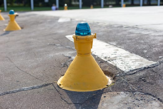 Close-up of a yellow runway marker with a blue light, indicating directions on the airport tarmac