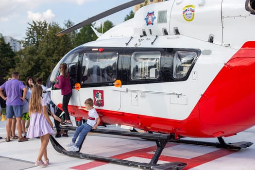 Moscow, Moscow region, Russia - 03.09.2023:Children and adults walk near an ambulance rescue helicopter, on a sunny summer day.