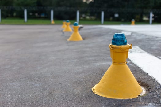 Row of yellow airfield ground lights with blue tops, used for runway and taxiway guidance at an airport