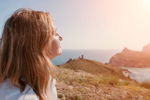 Woman travel sea. Young Happy woman in a long red dress posing on a beach near the sea on background of volcanic rocks, like in Iceland, sharing travel adventure journey