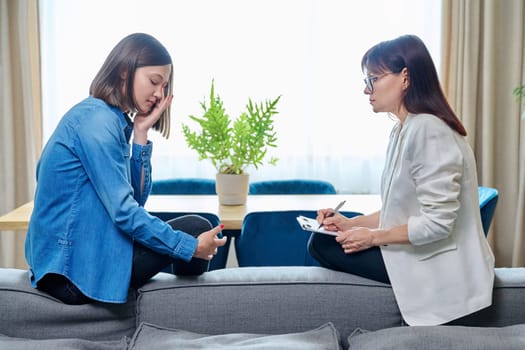 Sad crying young 20s woman in meeting with female psychologist therapist counselor sitting on couch in office. Psychology, therapy, psychotherapy, treatment, mental health, help, support