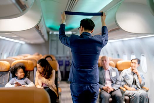 Airline staff man demonstration and explain about safety tools, safety belt, in the airplane to the passenger before the flight in airport area.