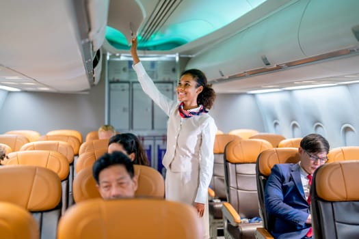 Air hostess walk to close luggage compartment of airplane before take off and bring the passenger to the destination with happiness.