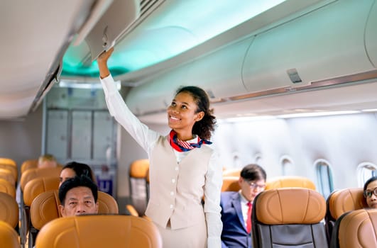 Wide shot of air hostess walk to close luggage compartment of airplane before take off and bring the passenger to the destination with happiness.