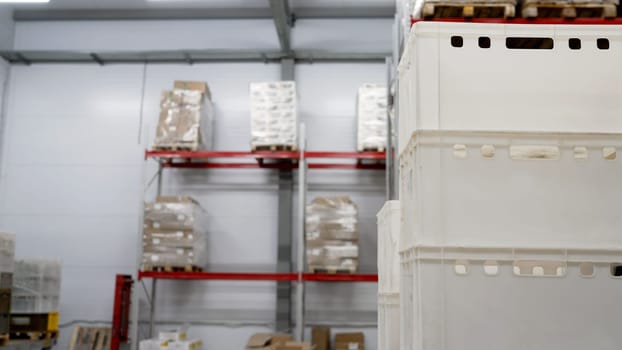 Small industrial warehouse with racks. Small warehouse with boxes and plastic containers. Plastic trays and cardboard boxes on metal racks.