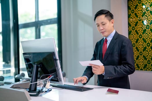 Airline staff man use computer to check detail and service to passenger at counter in the airport.