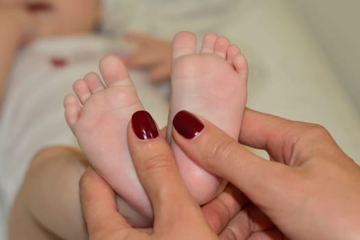 Mother makes massage on the foot of baby with oil
