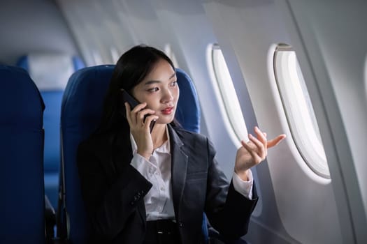 Successful young asian business woman sits in airplane cabin plane and working from anywhere. Flying at first class.