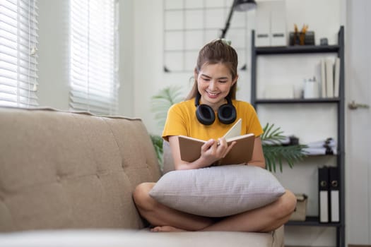 Young pretty woman siting on sofa and reading a book enjoys of rest. relaxing at home.