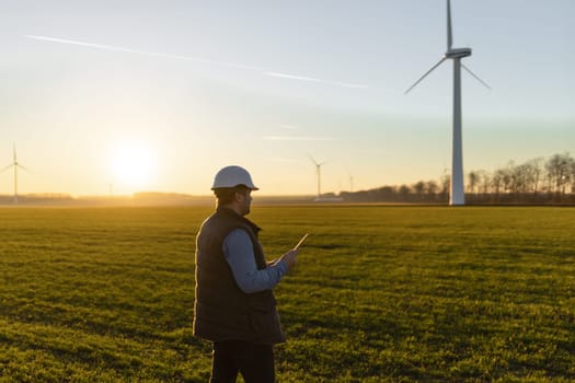 Businessman checking on wind turbine energy production.